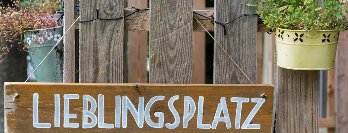 Schild Lieblingsplatz hängt an einem Holzzaun